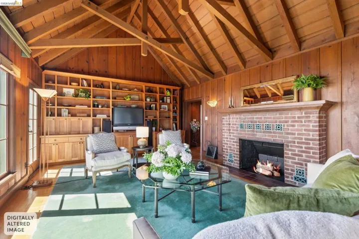 Spacious living area featuring extensive wood paneling, an exposed beam vaulted ceiling, large picture windows with Bay views, built-in shelving, fireplace and hardwood floors