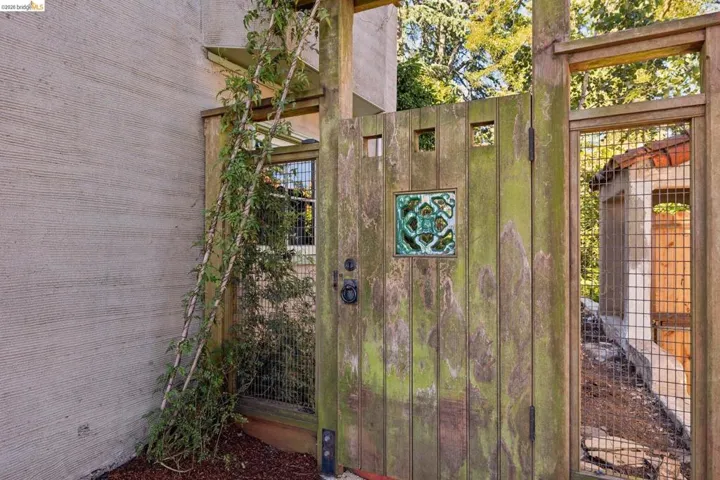 Wooden gate with decorative tile insert, metal hardware, and integrated square cut-outs