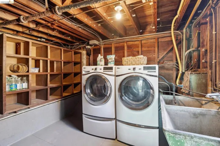 Laundry area featuring dual front-loading machines, a utility sink, and built-in shelving