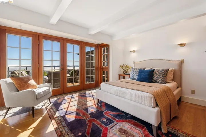 Hardwood flooring and white walls complement the beamed ceiling