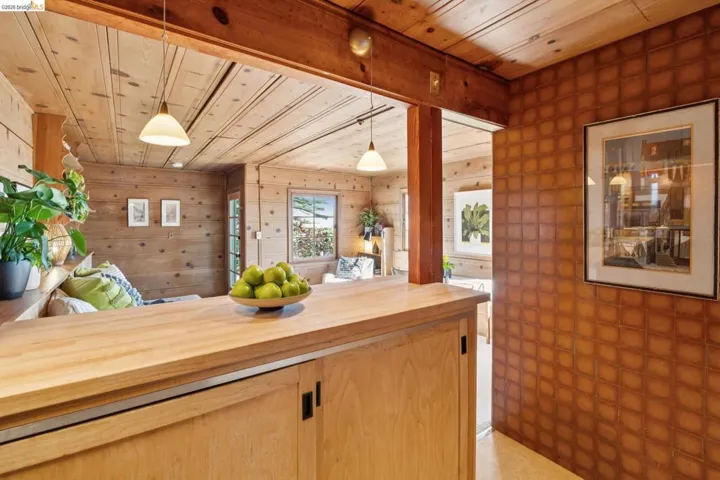 Wood-paneled interiors featuring a pass-through counter with light wood cabinetry, recessed lighting, and a textured accent wall