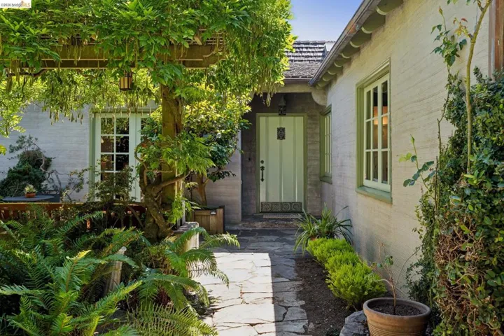 Stone pathway leading to a prominent light green entry door with decorative hardware