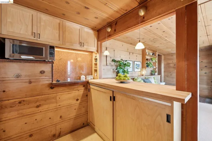 Kitchen pass-through window with wood-finish cabinetry and paneled walls