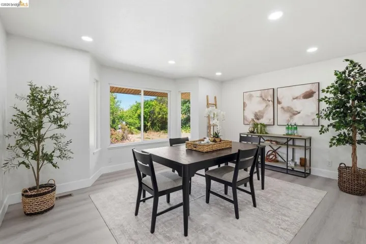 Dining area featuring bay windows, light wood-finish flooring, recessed lighting, and crisp white walls