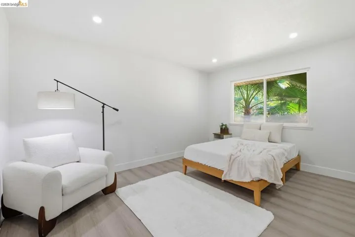 Recessed ceiling lighting illuminates a room featuring light-toned wood-finish flooring and white walls