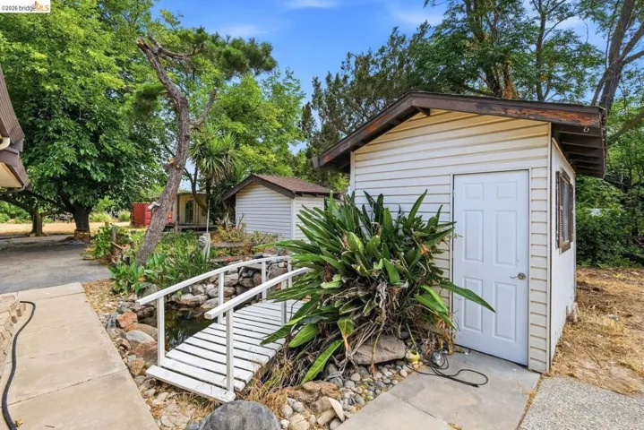 Detached shed with vinyl siding, a paneled door, and an exterior window