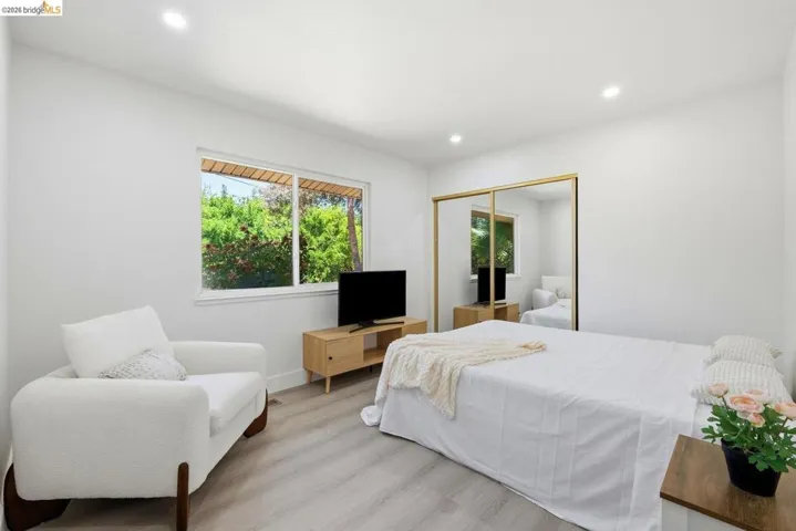 Recessed ceiling lighting illuminates a room featuring light-toned wood-finish flooring and white walls