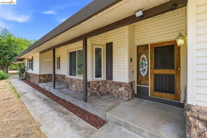 Exterior entry featuring light-colored siding and a stone facade