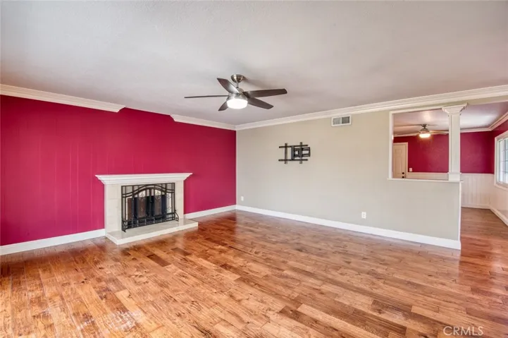 Living room with cozy fireplace and ceiling fan with easy flow to kitchen.