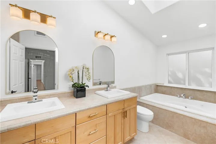 Primary bathroom with double vanity, vaulted ceiling and skylight.