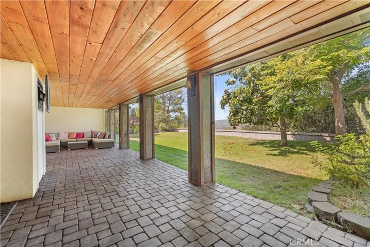 Large covered patio with wood ceiling, slate columns, built in lighting and speakers.
