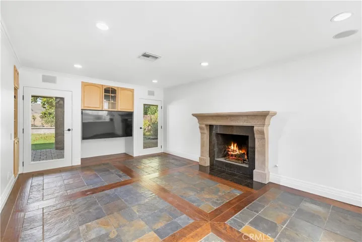 Family room with Venetian finished gas fireplace, wood and slate floor, built-in tv and stereo cabinets, and glass doors to covered patio and mountain views.