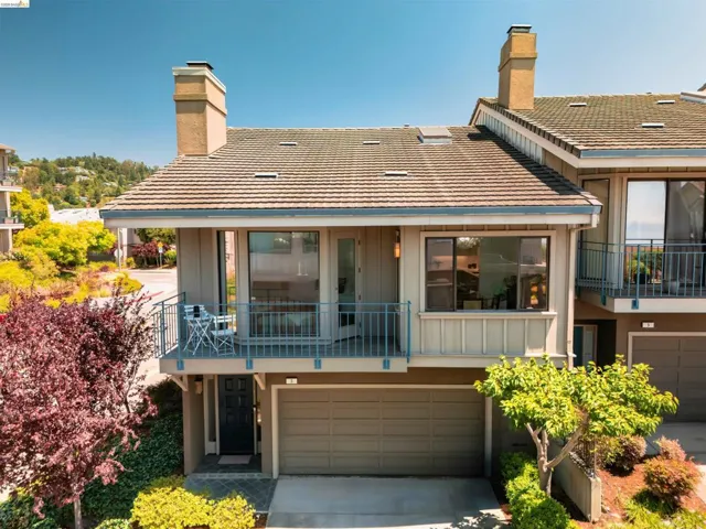 Multi-level facade featuring a private balcony with metal railing, an attached garage, and a tiled roof