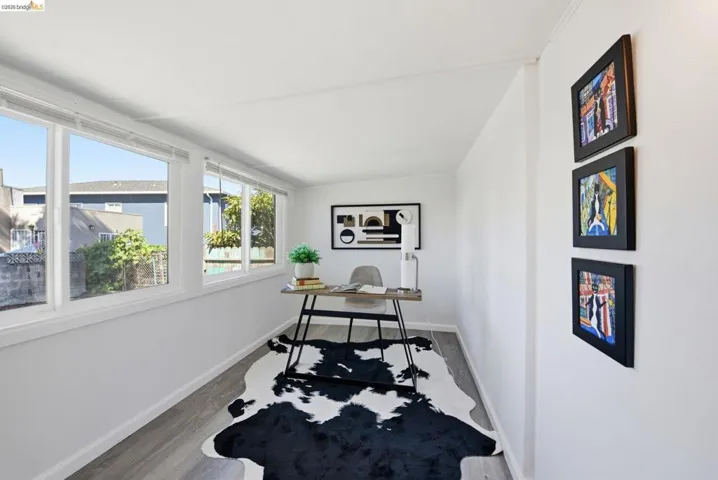 Light-filled room featuring a wall of multiple windows, clean white walls, and wood-finish flooring