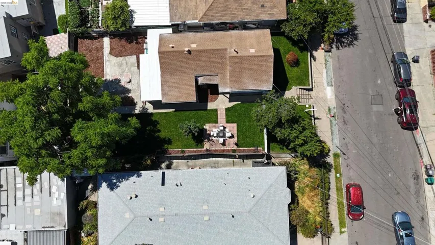 Property featuring a shingle roof, green lawn, established trees, and a paved front path