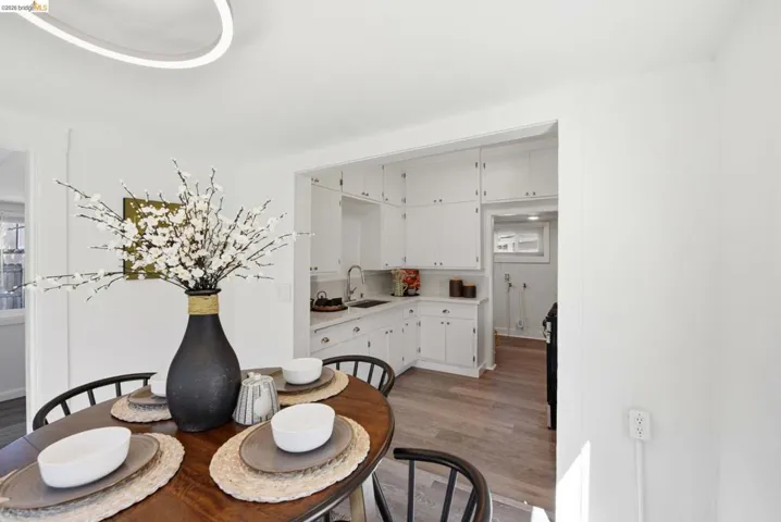Bright kitchen featuring abundant white cabinetry, stainless steel sink, light countertops, and wood-finish flooring