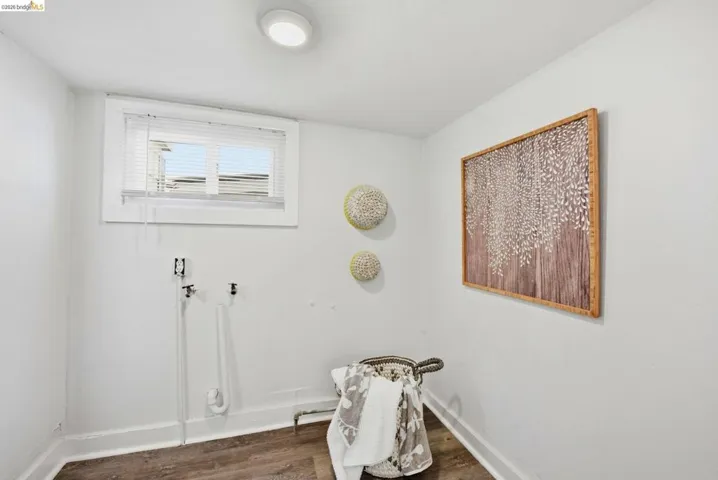 Dedicated laundry area featuring wood-finish flooring, white walls, and a recessed ceiling light
