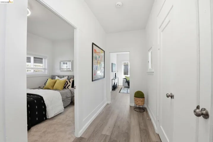 Bright hallway featuring wood-finish flooring, white painted walls, and white trim