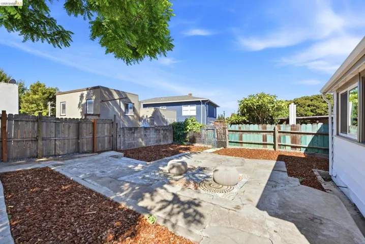 Spacious outdoor area with concrete patio sections and wood chip landscaping