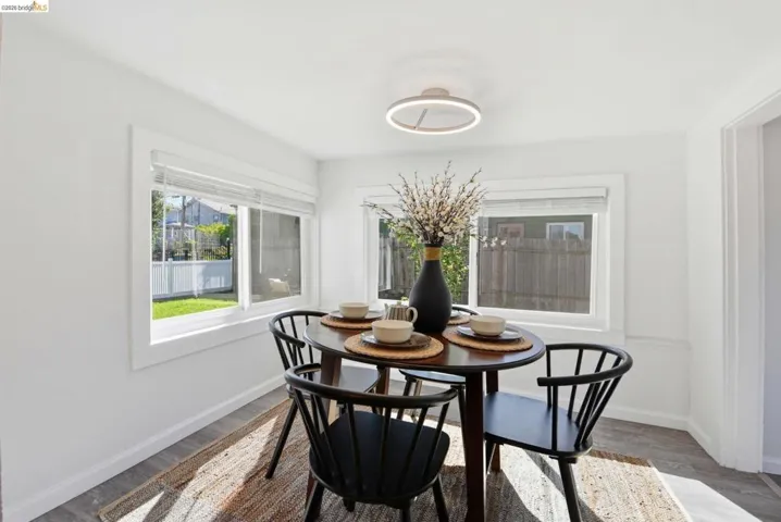 Bright dining area featuring multiple windows, wood-finish flooring, white walls, a contemporary ceiling light fixture, and white trim