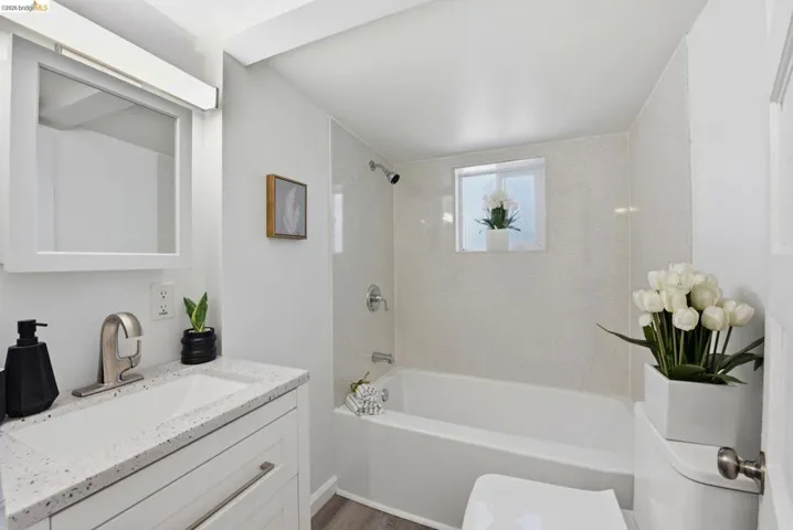 Bathroom featuring a white vanity with a speckled countertop, a rectangular undermount sink, and a brushed nickel faucet