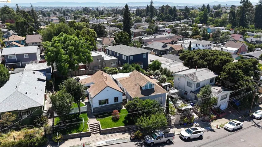 Residential streetscape featuring a single-family residence with a light-colored exterior and a brown shingle roof