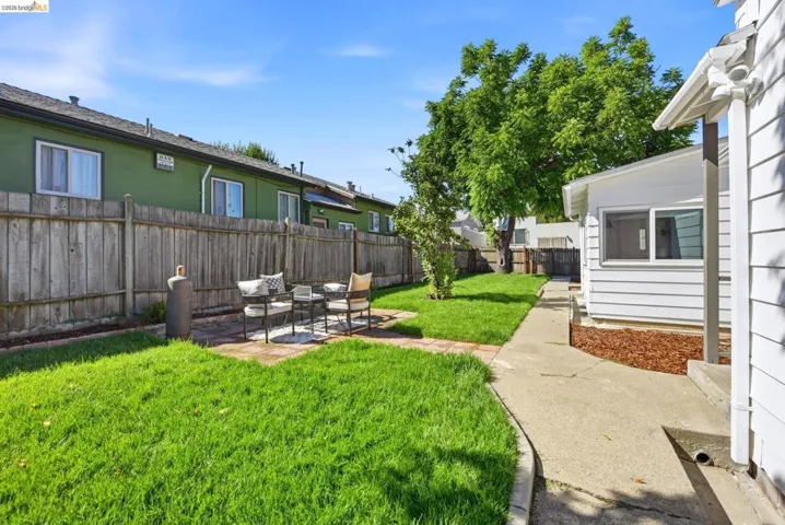 Expansive outdoor space featuring a manicured lawn, concrete pathway, and a defined patio area with brick pavers