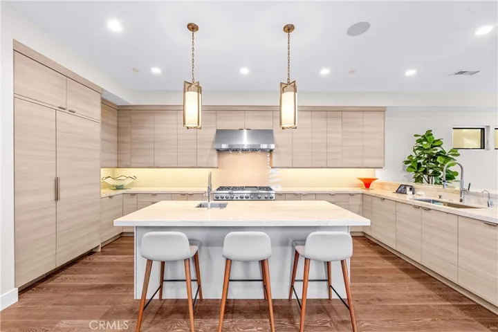 Gourmet kitchen features a Thermador 6-burner range with grill, double ovens, and a center island with a prep sink, built-in microwave and wine fridge.