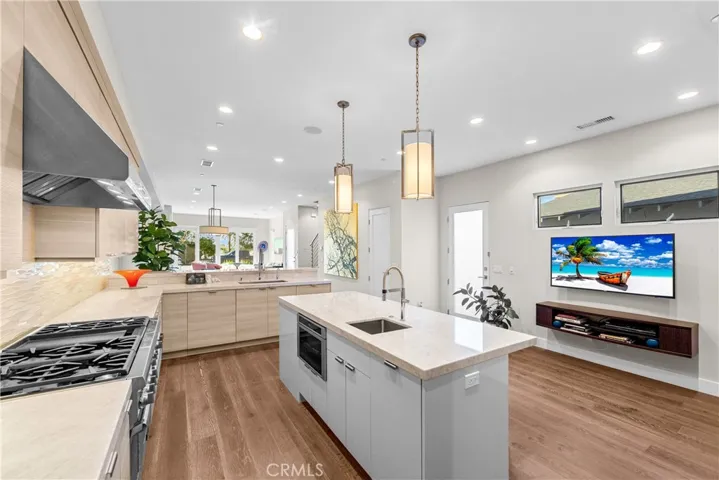 Gourmet kitchen features a Thermador 6-burner range with grill, double ovens, and a center island with a prep sink, built-in microwave and wine fridge.