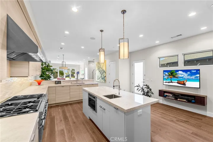 Gourmet kitchen features a Thermador 6-burner range with grill, double ovens, and a center island with a prep sink, built-in microwave and wine fridge.