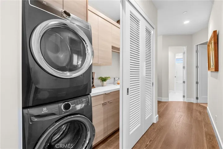 Thoughtfully designed laundry center features custom cabinetry utility sink, folding counter, hanging bar, and louvered doors that conceal the space when not in use.