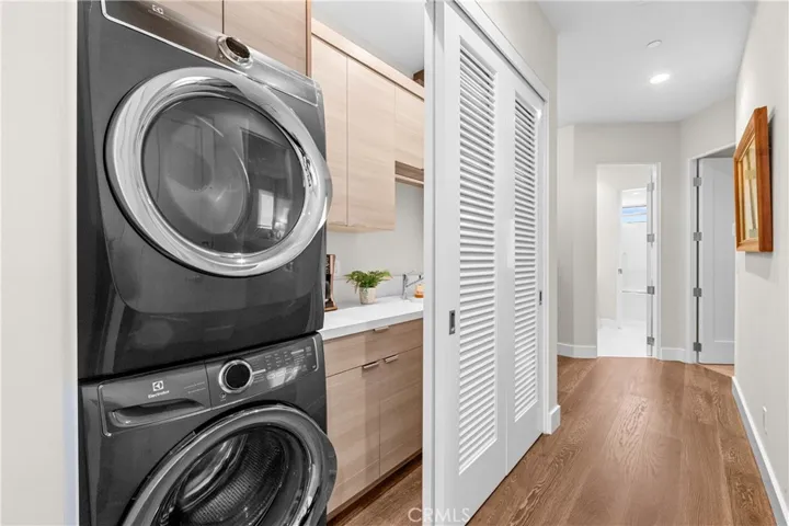 Thoughtfully designed laundry center features custom cabinetry utility sink, folding counter, hanging bar, and louvered doors that conceal the space when not in use.