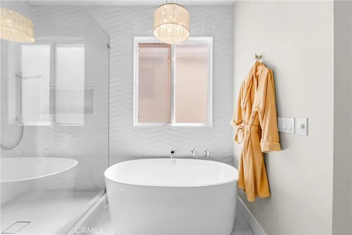 Spa-inspired primary bath showcases a Victoria + Albert soaking tub, seamless glass shower, designer lighting and impeccable finishes throughout.