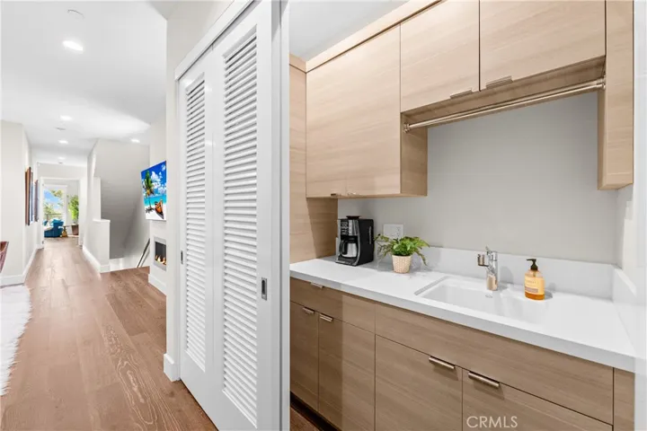Thoughtfully designed laundry center features custom cabinetry utility sink, folding counter, hanging bar, and louvered doors that conceal the space when not in use.