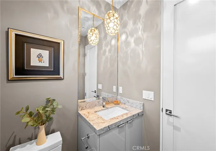 Elegant first-floor powder room featuring elegant stone countertops, designer lighting, and solid-core doors throughout.