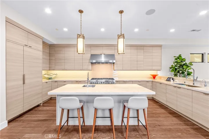 Gourmet kitchen features a Thermador 6-burner range with grill, double ovens, and a center island with a prep sink, built-in microwave and wine fridge.