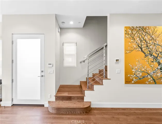 Dramatic entry showcases an engineered European white oak staircase with sleek custom stainless-steel railings.
