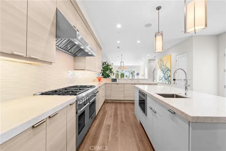 Gourmet kitchen features a Thermador 6-burner range with grill, double ovens, and a center island with a prep sink, built-in microwave and wine fridge.