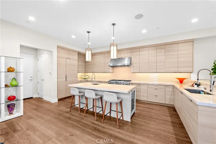 Gourmet kitchen features a Thermador 6-burner range with grill, double ovens, and a center island with a prep sink, built-in microwave and wine fridge.