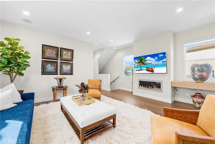 Light-filled family room features a cozy fireplace, wall-to-wall windows and an inviting sitting area at the top of the stairs