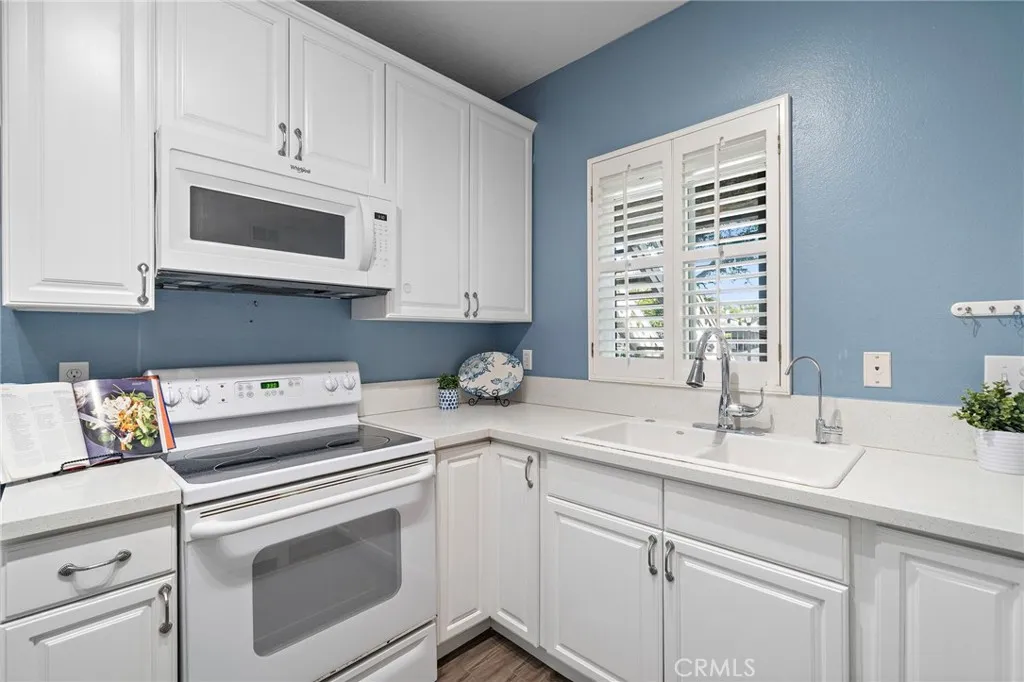 Kitchen: Well-appointed kitchen with quartz countertops, white cabinetry, and a window overlooking the patio.