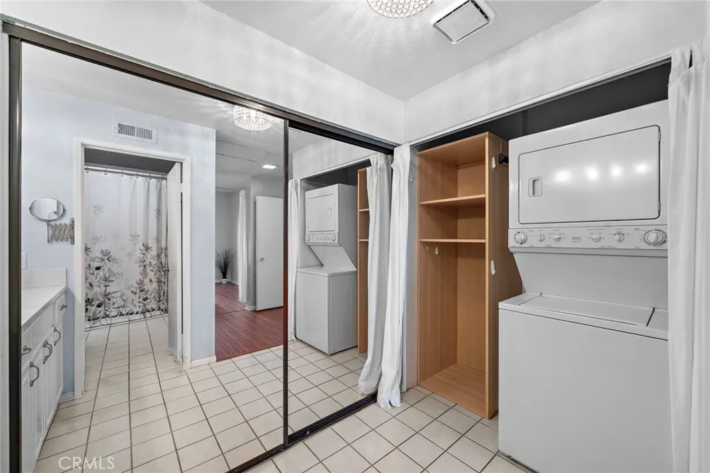 Laundry Area: Convenient indoor laundry area with a stackable washer and dryer, mirrored closet doors, and additional storage space.