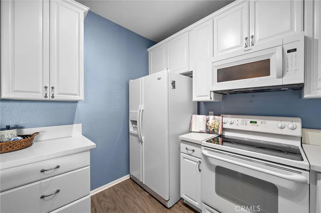 Kitchen: Bright kitchen with abundant cabinet storage, quartz countertops, and matching white appliances.