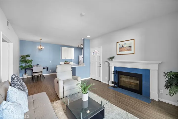 Living Room: Open-concept living room with a cozy fireplace, wood-look flooring, and seamless flow into the dining area and kitchen.