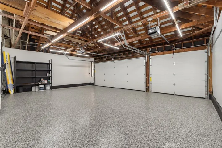 3 car garage with epoxy flooring, storage space above interior access door, and Tesla Universal Charger
