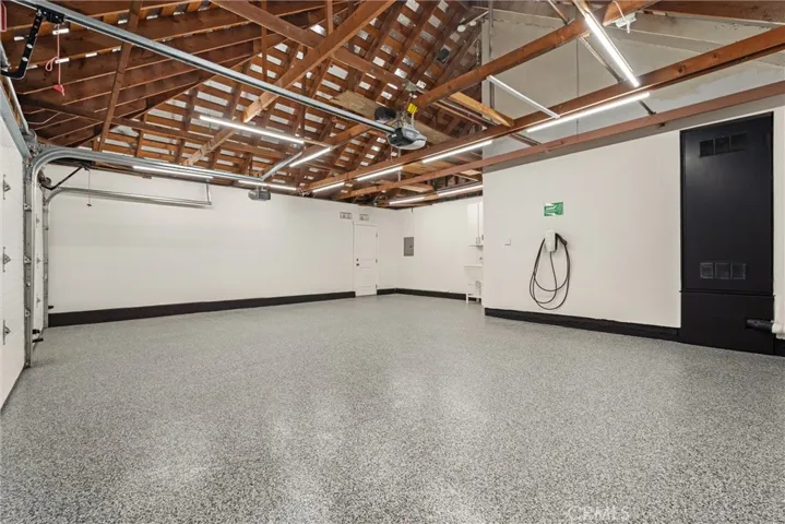 3 car garage with epoxy flooring, storage space above interior access door, and Tesla Universal Charger