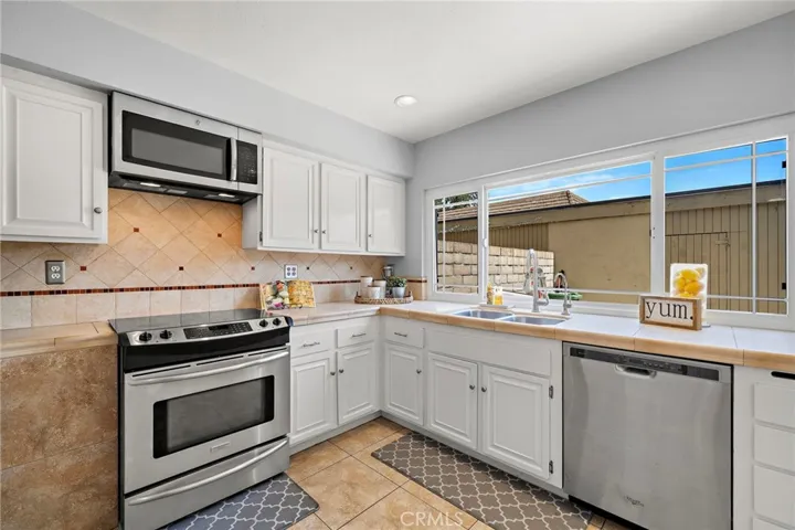 Recessed lighting, tile countertops, white shaker cabinetry
