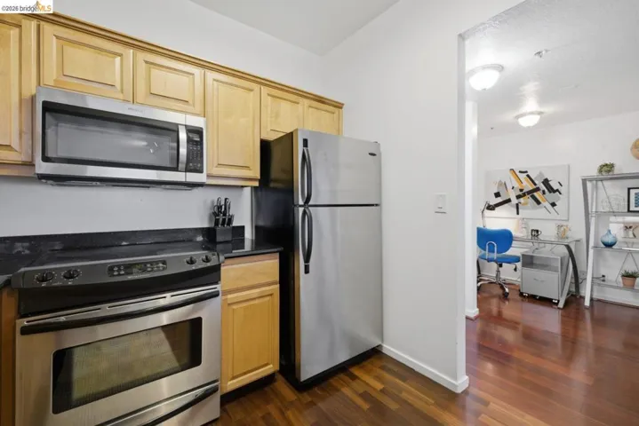 Kitchen featuring stainless steel appliances, wood-finish flooring, and light wood cabinetry