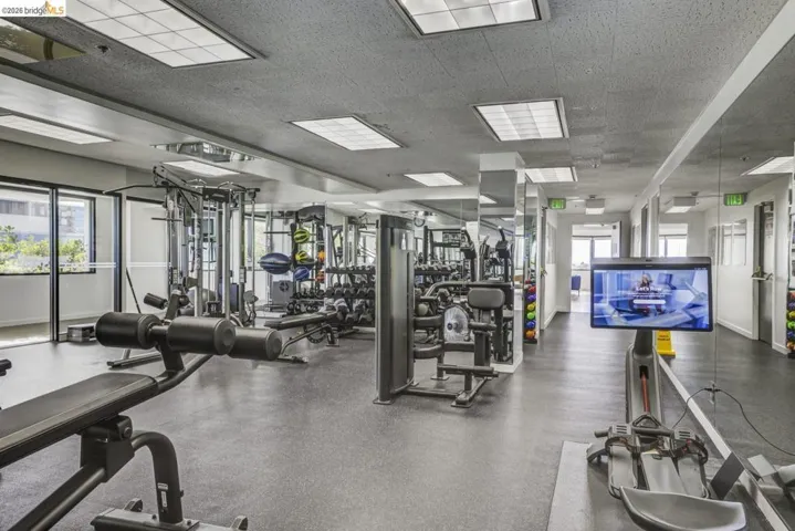 Fitness center featuring extensive mirrored walls, recessed lighting, rubber flooring, and large windows