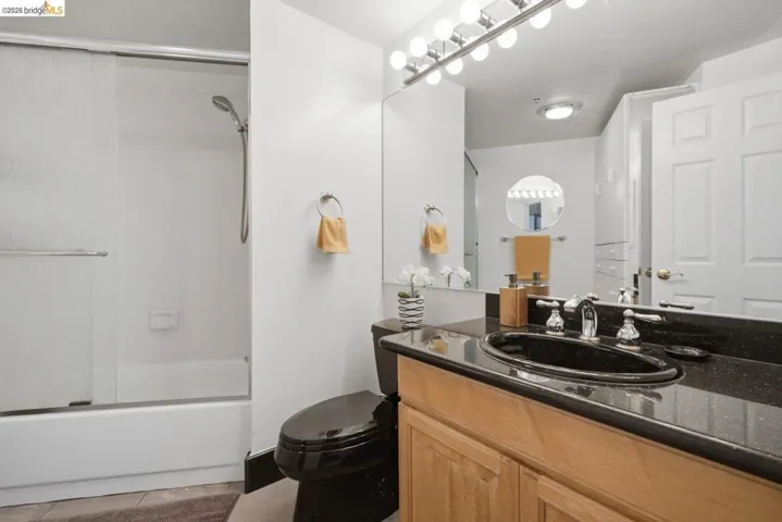 Bathroom featuring a black toilet, black under-mount sink, and black speckled countertop